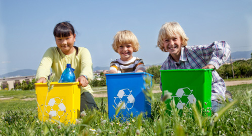 Photo of three kids with small recycling bins.